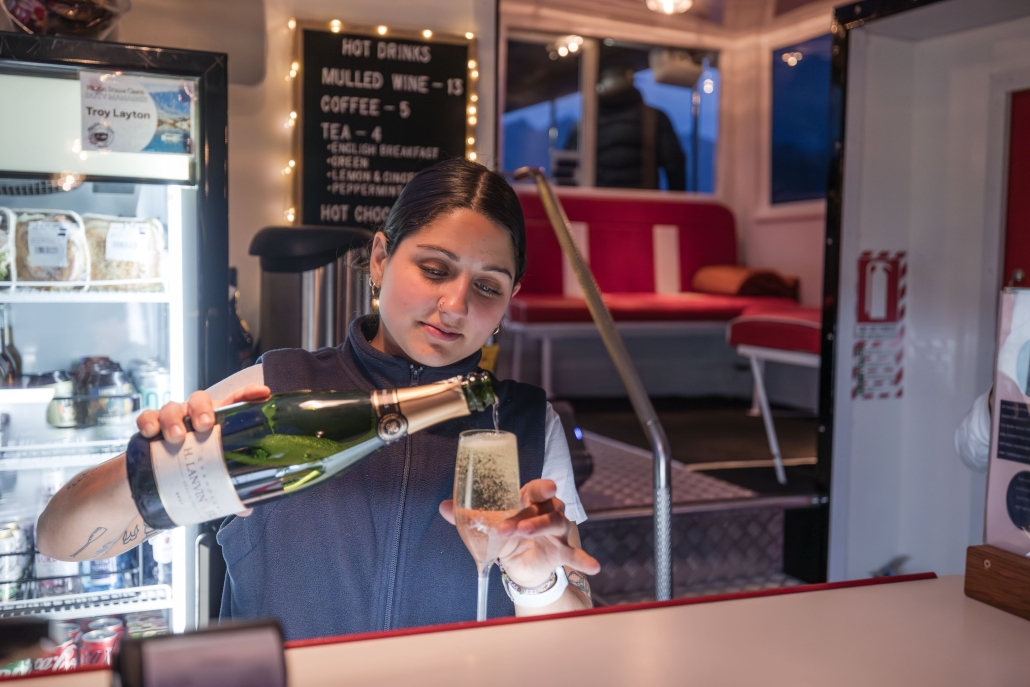Queenstown Twilight Cruise, Evening Cruise Woman pouring champagne into a flute on a cruise.