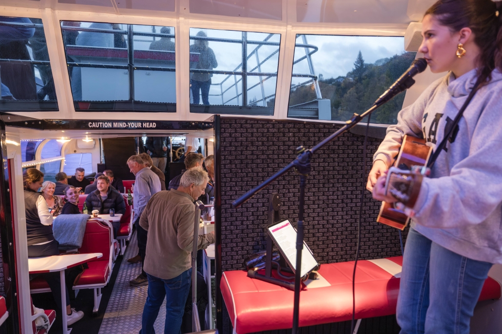 Female musician performing with acoustic guitar and microphone on a cruise.