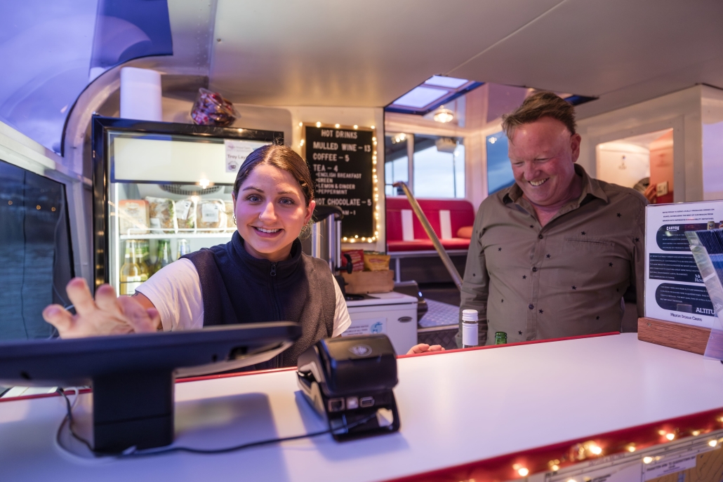 Queenstown Twilight Cruise, Evening Cruise Smiling cashier serving a happy customer on a cruise.